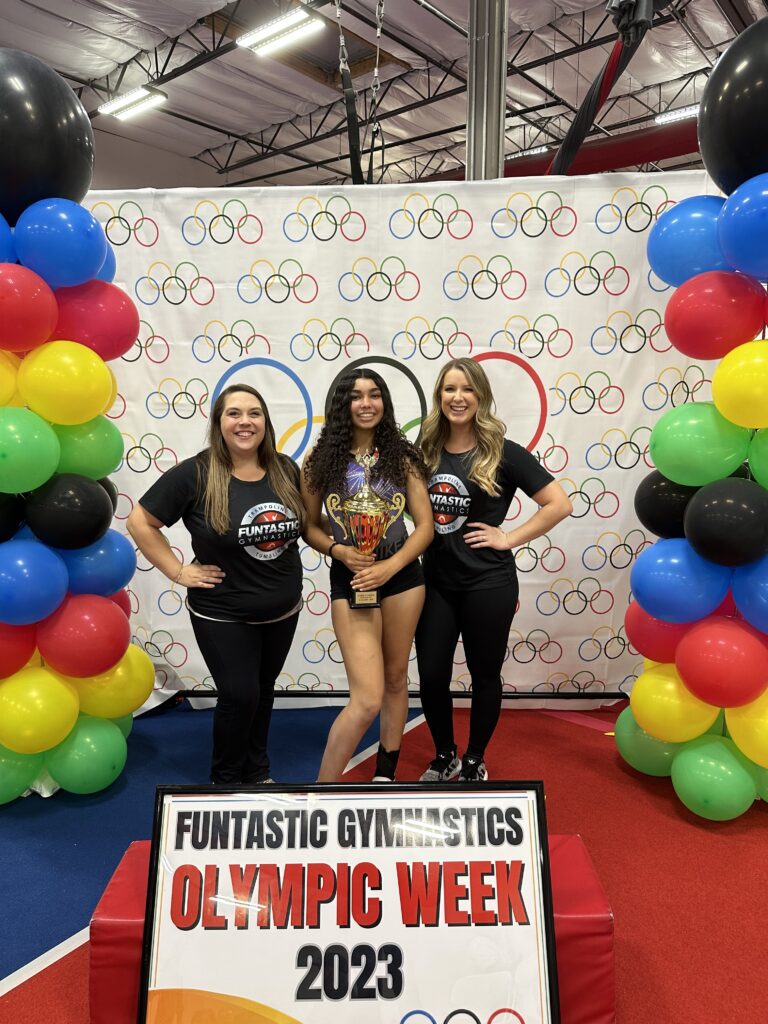 Three girls posing for a picture in front of the olympic theme.
