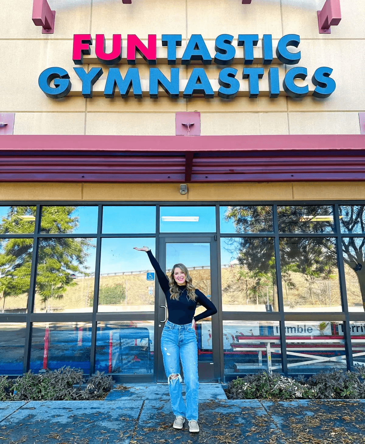 A woman standing in front of a building with the words " funtastic gymnastics ".