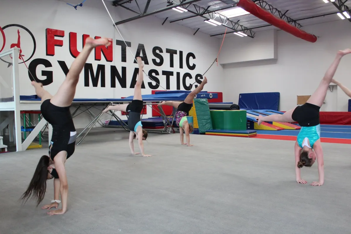 A group of people doing handstands in an indoor gym.